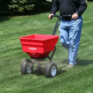 man pushing broadcast spreader